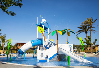 Parco giochi acquatico con scivoli e palme presso La Llosa 3 LLEBEIG, Spagna, in una giornata soleggiata.