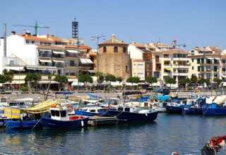 Vue sur le port de plaisance avec des bateaux colorés et des immeubles depuis un hébergement glamping.