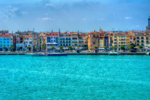 Immagine di edifici colorati e barche a vela al porto, vista dall’acqua presso un glamping
