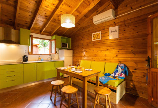 Cucina luminosa e zona pranzo in bungalow di legno a «La Llosa Mestral- BUNGALOWS-G» in Spagna con mobili verdi.