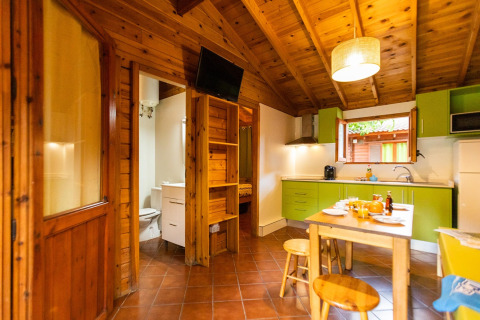 Accogliente bungalow in Spagna con interni in legno, cucina verde e tavolo da pranzo vicino al bagno.