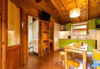 Accogliente bungalow in Spagna con interni in legno, cucina verde e tavolo da pranzo vicino al bagno.