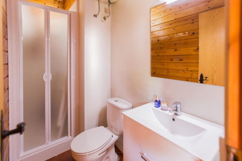 Bagno moderno con doccia, WC, lavabo bianco e legno presso La Llosa Mestral Bungalows in Spagna.