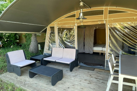 Zona de estar exterior de una tienda safari con muebles modernos en Camping Le Clou 1, Francia.