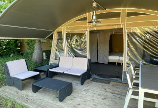 Zona de estar exterior de una tienda safari con muebles modernos en Camping Le Clou 1, Francia.