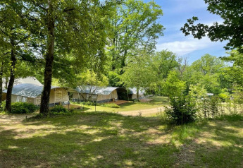Tiendas safari en Camping Le Clou 1 en Francia, rodeadas de árboles y césped verde bajo el cielo azul.