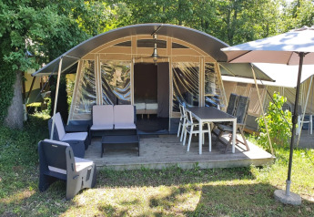 Tienda safari en Camping Le Clou 1 con terraza amueblada, mesa exterior, sillas y sombrilla grande.