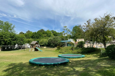 Parque infantil con dos camas elásticas, tobogán y columpios en Camping Le Clou 1, Francia.