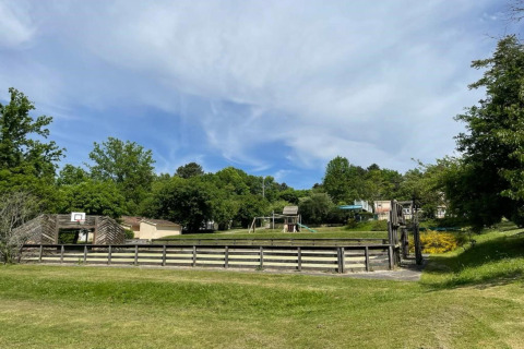 Vista del parque infantil y la cancha de baloncesto en Camping Le Clou 1, rodeados de naturaleza en Francia.