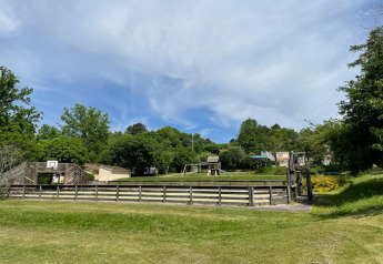 Vista del parque infantil y la cancha de baloncesto en Camping Le Clou 1, rodeados de naturaleza en Francia.