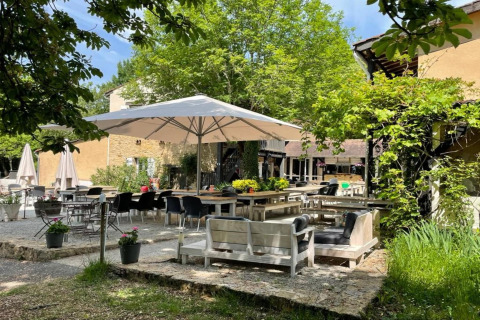 Gemütlicher Terrassenbereich auf Camping Le Clou 1 in Frankreich mit Sitzgruppen unter Sonnenschirmen.