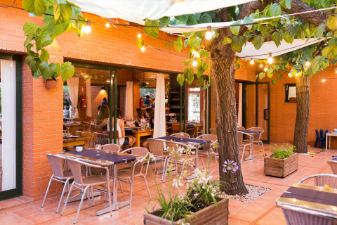 Cortile esterno di La Llosa Mestral Bungalows-G in Spagna con tavoli, sedie, alberi e luci decorative.