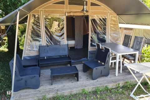 Terraza de tienda safari en Camping Le Clou 1, Francia, con muebles exteriores y mesa para comer.