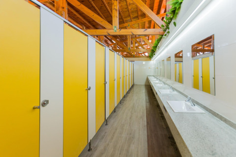 Bagno pubblico moderno a La Llosa Mestral-BUNGALOWS-G in Spagna, con cabine gialle e zona lavandini.