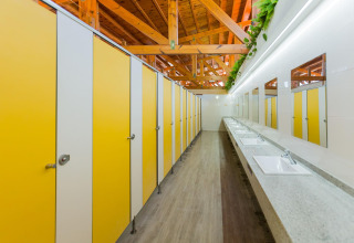 Bagno pubblico moderno a La Llosa Mestral-BUNGALOWS-G in Spagna, con cabine gialle e zona lavandini.