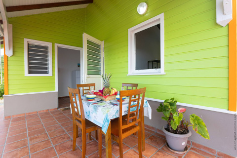 Terraza exterior con mesa preparada para cuatro personas frente a una cabaña verde en Portugal.