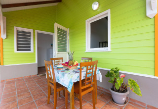Terraza exterior con mesa preparada para cuatro personas frente a una cabaña verde en Portugal.