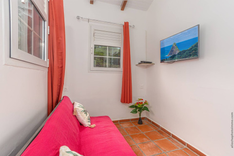 Acogedora sala en Bungalow «avec piscine au cœur de la campagne Vert» con sofá rosa y TV en la pared.