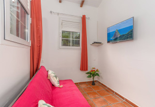 Acogedora sala en Bungalow «avec piscine au cœur de la campagne Vert» con sofá rosa y TV en la pared.