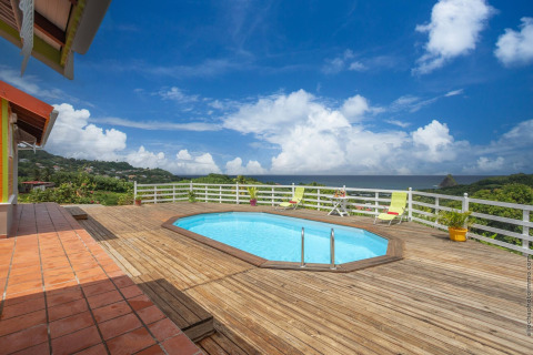 Piscina al aire libre con terraza de madera y vistas panorámicas al mar y colinas en Bungalow Vert, Portugal.