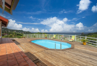 Piscina al aire libre con terraza de madera y vistas panorámicas al mar y colinas en Bungalow Vert, Portugal.