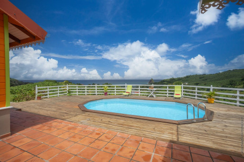 Piscina en terraza de madera con vistas panorámicas a las colinas y cielo en el bungalow con piscina en Portugal verde.