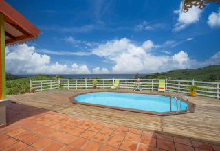 Piscina en terraza de madera con vistas panorámicas a las colinas y cielo en el bungalow con piscina en Portugal verde.
