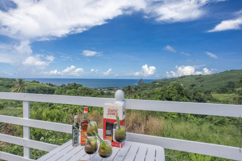 Bebidas sobre una mesa en un alojamiento glamping con vistas a colinas verdes y al mar azul.