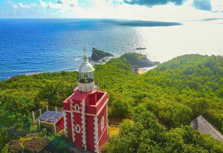 Vista aérea de un faro rojo en la costa verde con vistas al océano atlántico en Portugal al atardecer.