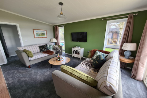 Stue i New Puddledock lodge, Storbritannien, med grøn væg, moderne møbler og fladskærms-tv.