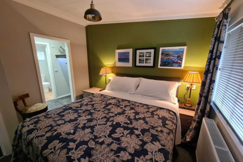 Hyggeligt soveværelse på New Puddledock Lodge i Storbritannien med grøn væg og dobbeltseng.