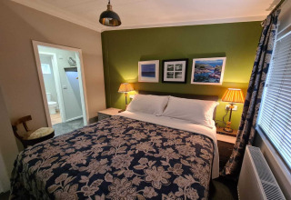 Hyggeligt soveværelse på New Puddledock Lodge i Storbritannien med grøn væg og dobbeltseng.