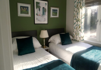 Chambre lumineuse à deux lits simples avec mur vert, grande fenêtre et déco moderne au New Puddledock Lodge.