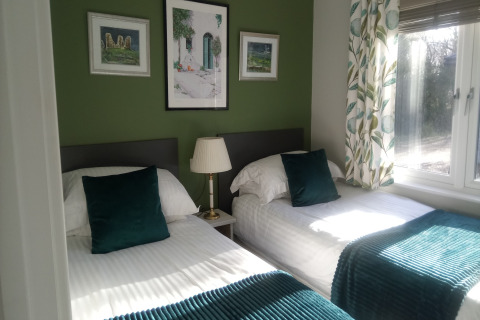 Lyst dobbeltværelse i New Puddledock Lodge, Storbritannien, med grønne puder og udsigt til haven.