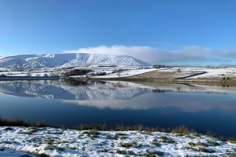 Snedækket landskab ved New Puddledock lodge i Storbritannien med bjerge og sø, der spejler sig.