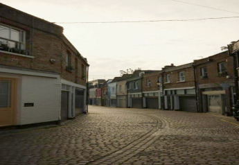 Rue pavée avec hébergements glamping au coucher du soleil, ambiance paisible et pittoresque.