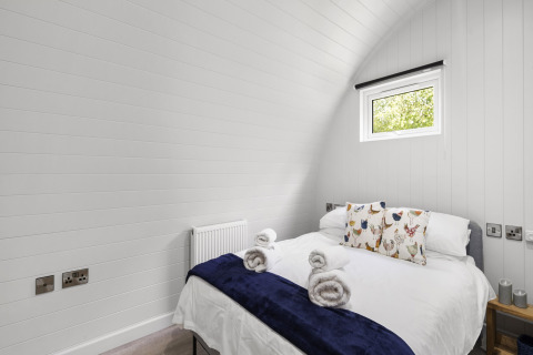Lichte slaapkamer in The Chicken Coop pod in het Verenigd Koninkrijk met tweepersoonsbed, kussens en handdoeken.