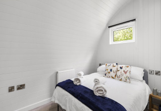 Lichte slaapkamer in The Chicken Coop pod in het Verenigd Koninkrijk met tweepersoonsbed, kussens en handdoeken.
