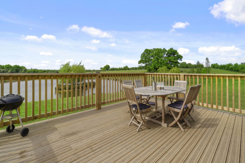 Houten terras met tafel, stoelen en barbecue met uitzicht op meer bij The Chicken Coop in het VK.