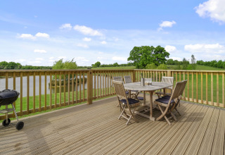 Houten terras met tafel, stoelen en barbecue met uitzicht op meer bij The Chicken Coop in het VK.