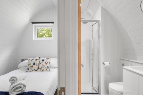 Minimalistische slaap- en badkamer met gebogen witte wanden in The Chicken Coop pod in het Verenigd Koninkrijk.