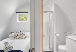 Minimalistische slaap- en badkamer met gebogen witte wanden in The Chicken Coop pod in het Verenigd Koninkrijk.