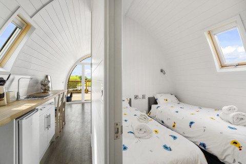 Binnenaanzicht van The Chicken Coop pod in het VK met compacte keuken en tweepersoons slaapkamer met dakramen.