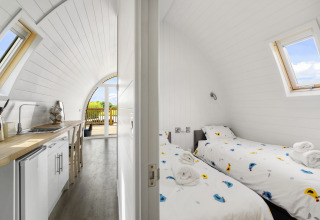 Binnenaanzicht van The Chicken Coop pod in het VK met compacte keuken en tweepersoons slaapkamer met dakramen.