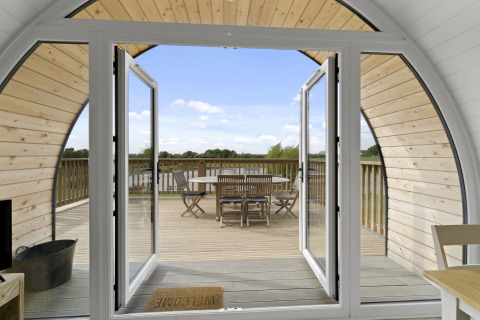 Uitzicht vanuit The Chicken Coop pod in het VK met open deuren naar het terras en buitenzitje.