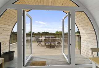 Uitzicht vanuit The Chicken Coop pod in het VK met open deuren naar het terras en buitenzitje.