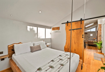 Camera da letto al Hillfarrow Hideaway con letto in legno, porta scorrevole rustica e atmosfera accogliente.