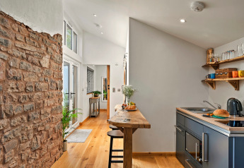 Cucina moderna in cabina presso Hillfarrow Hideaway, Regno Unito, con legno e muro in mattoni a vista.