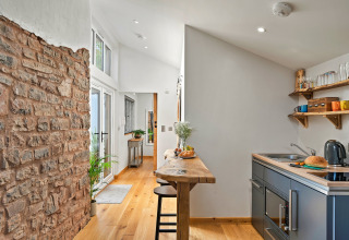 Moderne hytte køkken med træbordplade, synlig murstensvæg og naturligt lys ved Hillfarrow Hideaway.