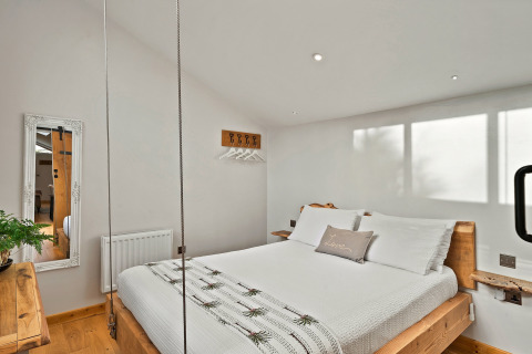 Lyst soveværelse i Hillfarrow Hideaway, UK, med træmøbler, hængeplanter og moderne indretning.